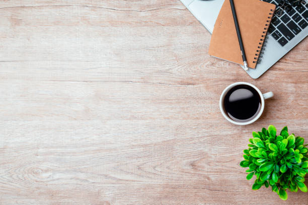 istock Work from home. desk office with laptop, blank notepad, coffee cup and pen on wood table. Flat lay top view copy spce. 1390949334