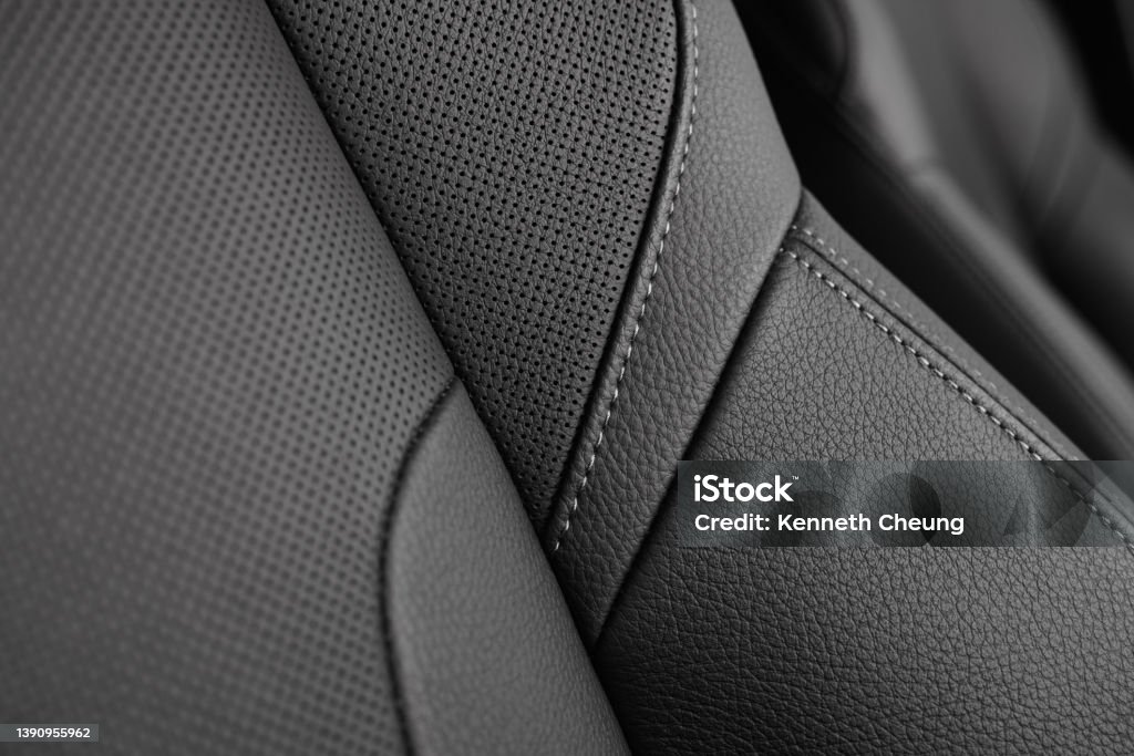 Perforated Leather Car Seat Stitching Closeup Closeup of a perforated leather seat with stitching detail in a modern sporty car.  Shallow focus.  Monochromatic. Leather Stock Photo