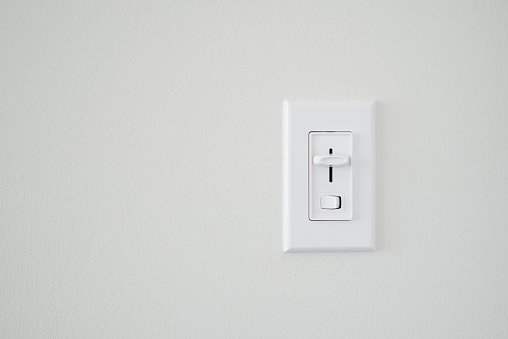 Single light dimmer switch on a blank white wall.