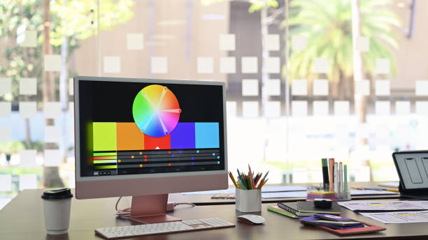 istock Design studio with computer, color swatches and wireframe sketches for mobile application on wooden table. 1390964058
