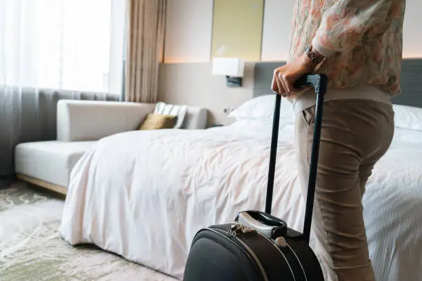 Asian young woman carrying a suitcase into the room in hotel close up, woman get into the room in luxury hotel. Asian woman tourist check-in and carry her baggage. Solo female tourist concept.