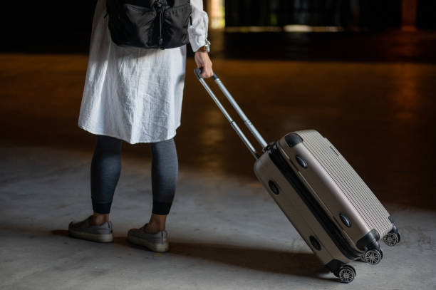 istock Fashionable woman pulling suitcase at street 1390971821