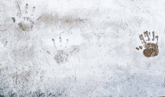 Three hand prints on outdoor old cement wall. Abstract grunge background texture. Copy Space