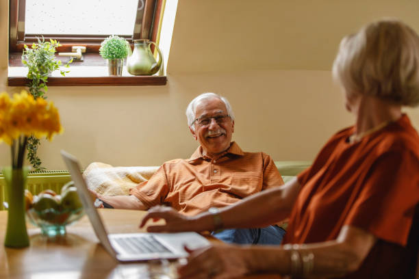 istock Joyful senior couple looking and smiling at each other while using technology 1390980060