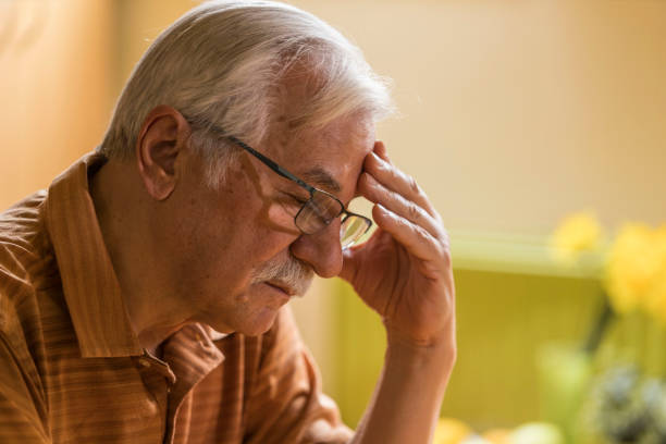 istock Senior man sitting with head in hand, looking down, worrying, contemplating 1390980487