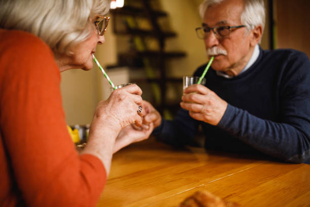 istock Romantic elderly couple holding hands and looking at each other while sipping lemonade 1390981274