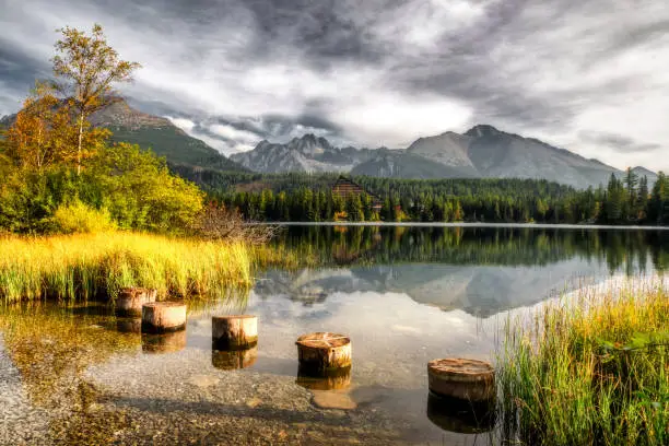 Dark cloudy day in mountain. Reflection of peaks on water surface of tarn Strbske pleso in High Tatras mountain at Slovakia