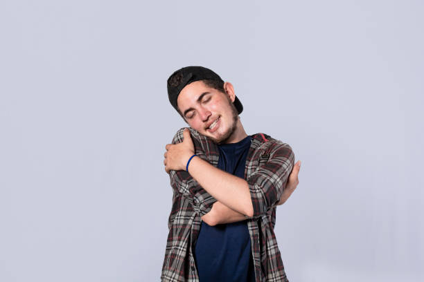istock Friendly man hugging himself, Pleased young man hugging himself, Attractive positive looking friendly young man with a sincere smile embracing himself gratefully 1390981527