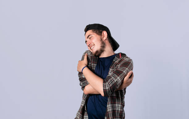 istock Friendly man hugging himself, Pleased young man hugging himself, Attractive positive looking friendly young man with a sincere smile embracing himself gratefully 1390981530