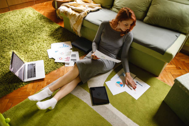istock Wide shot of female entrepreneur analyzing various documents while working from home 1390982319