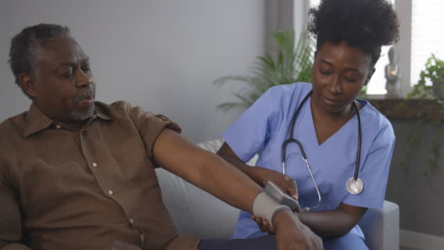 Caring nurse measures 70s patient blood pressure
