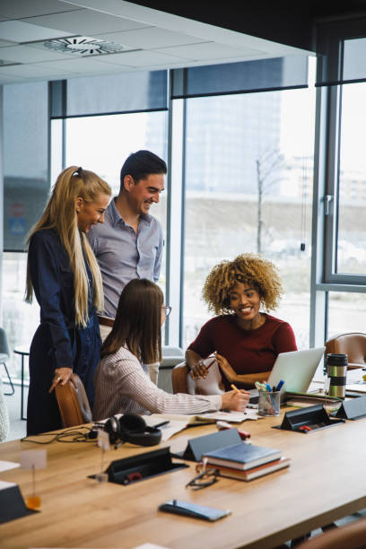 Four young business colleagues hanging out and chatting in a modern office stock photo