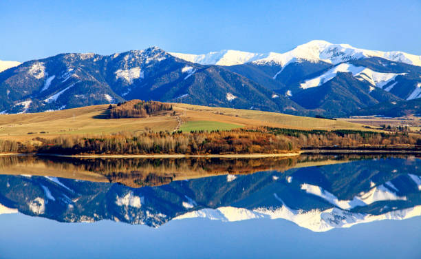 Reflection of snowy hills on water surface of lake stock photo