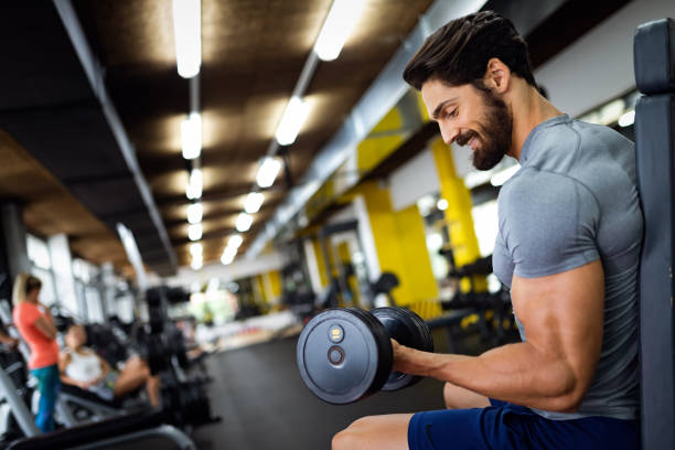 istock Muscular bodybuilder handsome man doing exercises in gym. Sport people workout concept 1390984199