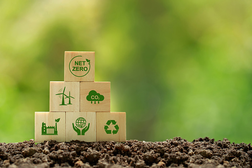 Net zero and carbon neutral concept.wooden cubes with netzero icons - renewable energy, co2 emissions reduction, green production, waste recycling.in green background