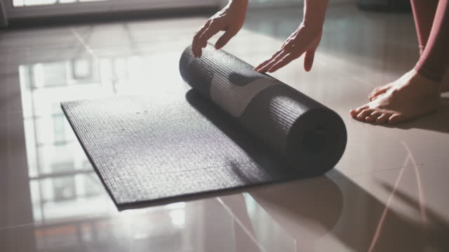 Woman rolling out yoga mat and preparing to meditate training in yoga