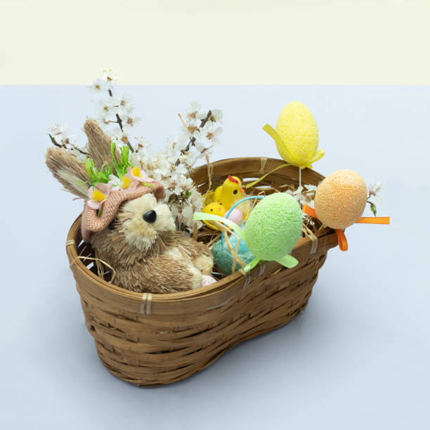 istock Easter bunny with Easter eggs, straw, flowers, chickens in a wicker basket. Minimalist concept of creative design. 1390988864