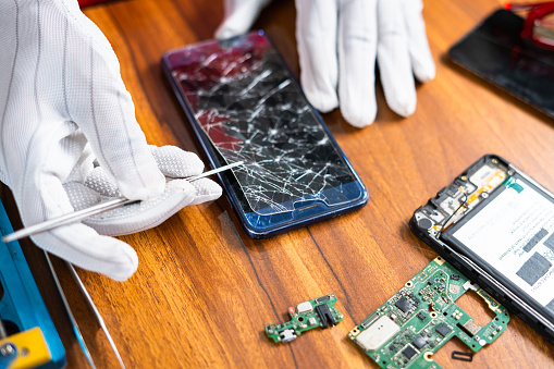 close up shot of technician removing or fixing broken mobile phone display at workshop - concept of skilled worker, professional occupation and small business.