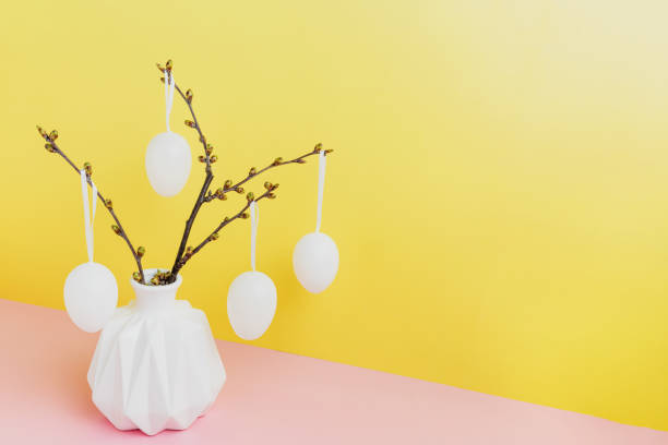 istock Happy Easter holiday, coming spring. Branches in white vase, hanging eggs 1390989168