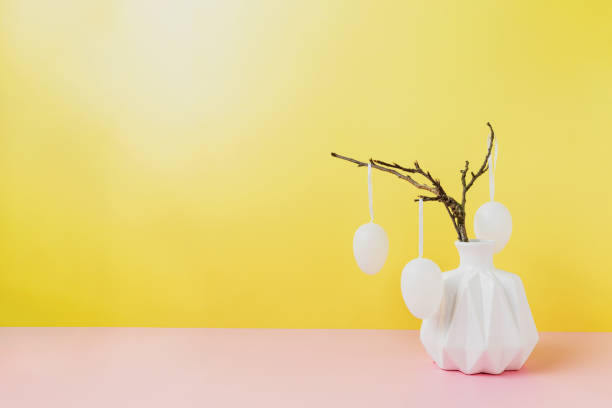 istock Happy Easter holiday, coming spring. Branches in white vase, hanging eggs 1390989459