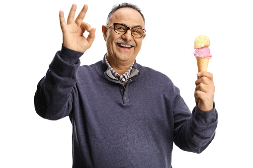 Happy mature man holding ice cream in a cone and gesturing good isolated on white background