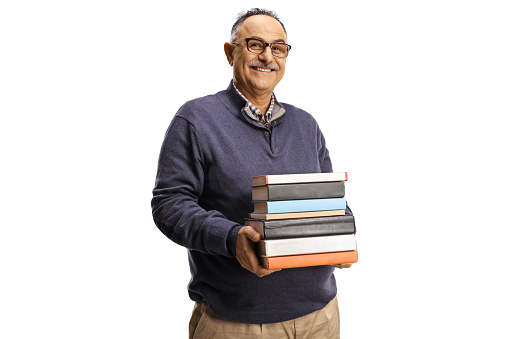 Smiling mature man holding a pile of books isolated on white background
