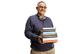 istock Smiling mature man holding a pile of books 1390990290