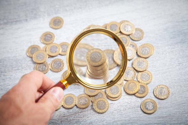istock Male hand magnifying coins. Inspect income 1390990710