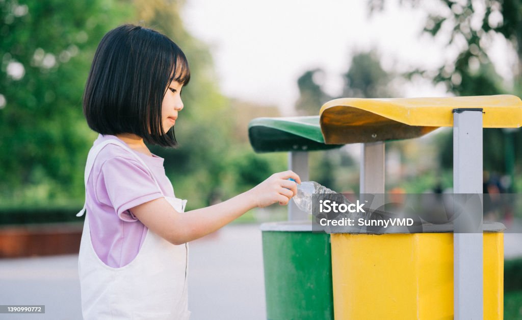 Image of Asian little girl puts used plastic bottles in the trash Garbage Stock Photo
