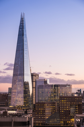 The iconic spire of The Shard rising high over the rooftops of London and the River Thames at sunset.