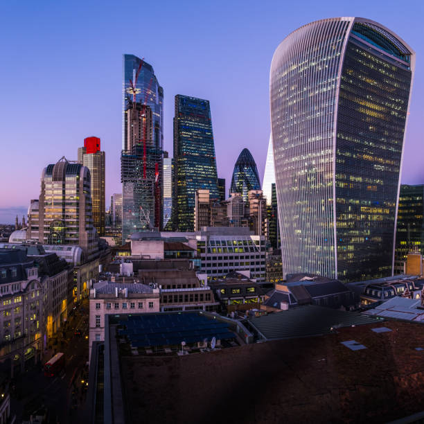 City of London futuristic skyscrapers twinkling dusk over Financial District The iconic curves of The Gherkin framed by the illuminated office buildings of the City of London’s Square Mile Financial District, UK. central london stock pictures, royalty-free photos & images