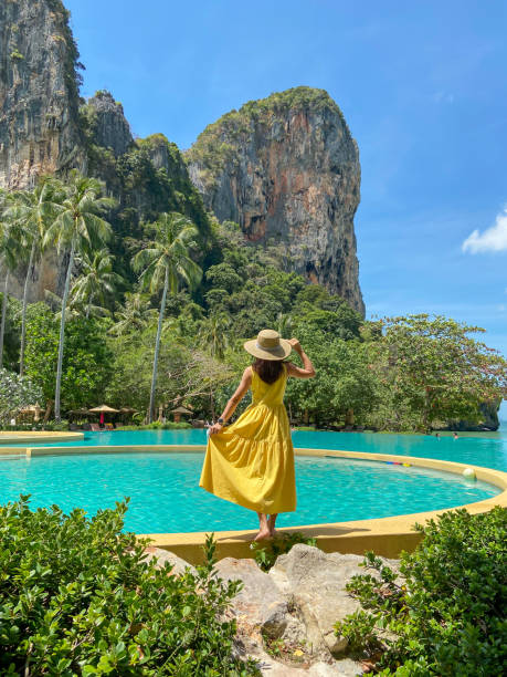 mulher turista de vestido amarelo e chapéu viajando na praia de railay, krabi, tailândia. férias, viagens, verão, wanderlust e conceito de férias - railay - fotografias e filmes do acervo
