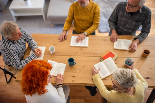 istock High angle view of senior Caucasian people reading and discuss the reference book 1390991767