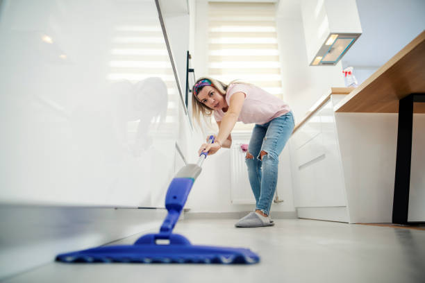 istock Tidy woman sweeping kitchen floor at home with mop and detergent. 1390993332