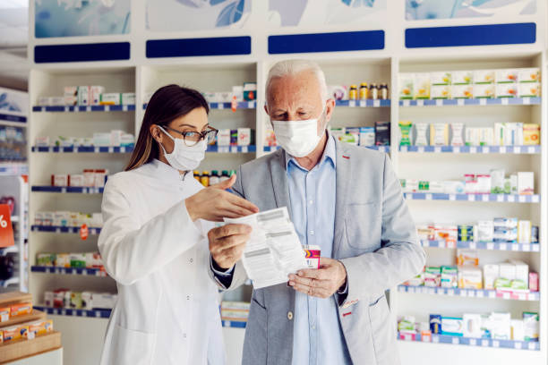 A pharmacy worker reading with patient side effects at pharmacy. stock photo