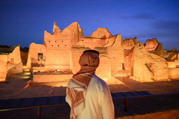 Rear view of Middle Eastern man in dish dash, kaffiyeh, and agal with focus on dramatic landscape of At-Turaif ruins near Riyadh. Property release attached.