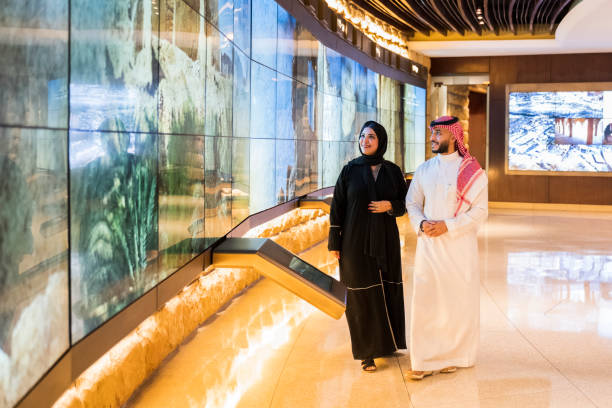 Couple admiring technology in At-Turaif visitor’s centre Full length view of Saudi man in dish dash, kaffiyeh, and agal and woman in abaya and hijab smiling as they watch history presented on modern video wall. Property release attached. 1814 stock pictures, royalty-free photos & images