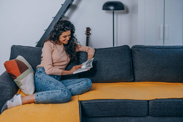istock Young beautiful woman reading a book on the couch. 1390994934