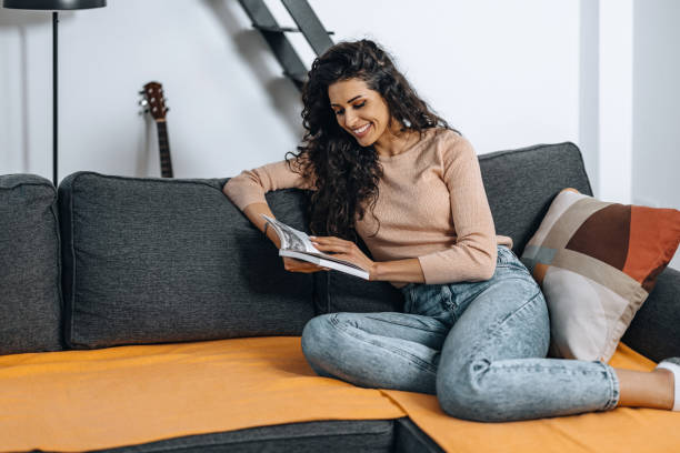 istock Young beautiful woman reading a book on the couch. 1390994951