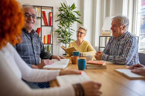 Group of Caucasian male and female friends, meeting for a club book, where they reading and discuss