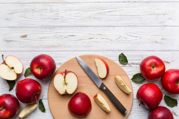 istock Fresh red apples with green leaves on table. cutting board with knife. Top view 1390999825
