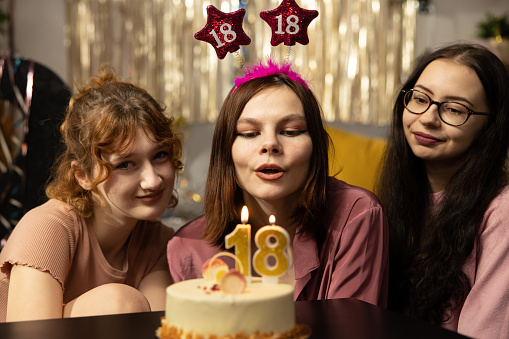 Portrait of girl looking at birthday cake surrounded by friends at party.