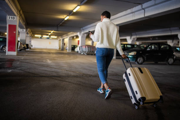 istock At the underground parking lot woman Black ethnicity pulling suitcase while using mobile phone 1391002416
