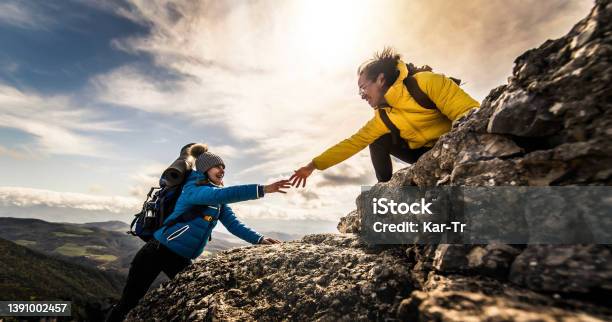 People Helping Each Other Hike Up A Mountain At Sunrise Giving Helping Hand And Teamwork Concept Stock Photo - Download Image Now