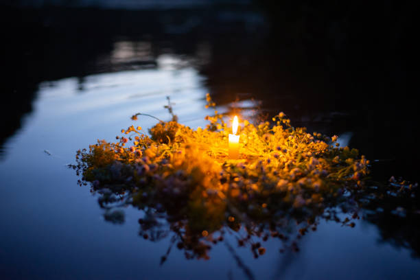 corona de flores silvestres con una vela flotando en el río - solsticio de verano fotografías e imágenes de stock