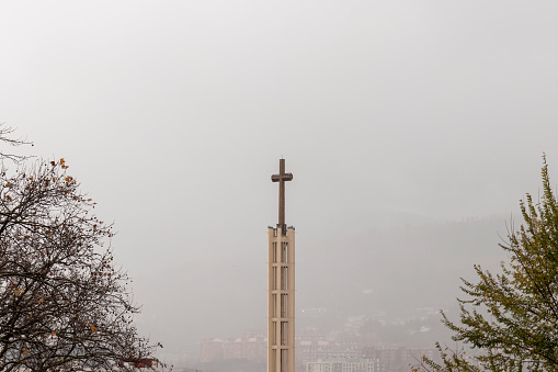 cross of a church in Bilbao on a foggy day