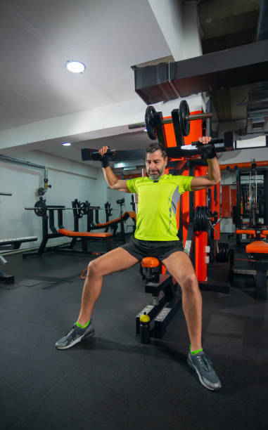istock Strong athletic middle-aged man exercise triceps with barbell on the bench in the gym 1391003041