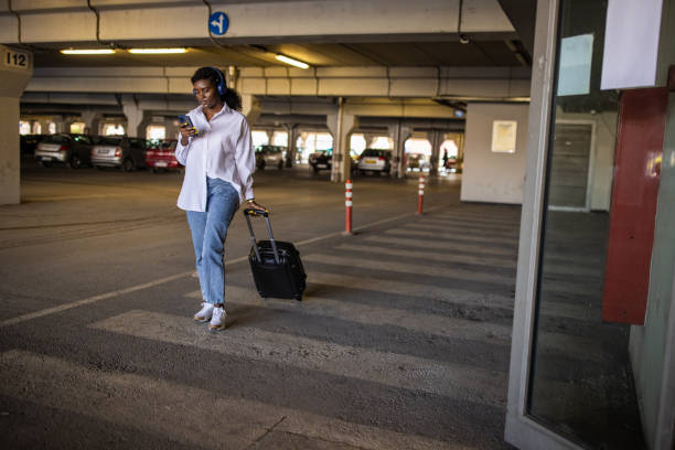 istock Woman Black ethnicity pulling suitcase while using mobile phone at the underground parking lot 1391003626