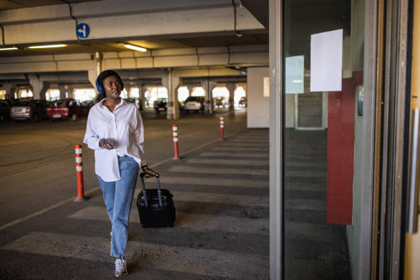 istock Woman Black ethnicity pulling suitcase while using mobile phone at the underground parking lot 1391003845