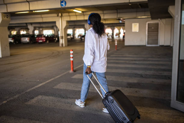 istock At the underground parking lot woman Black ethnicity pulling suitcase while using mobile phone 1391004007